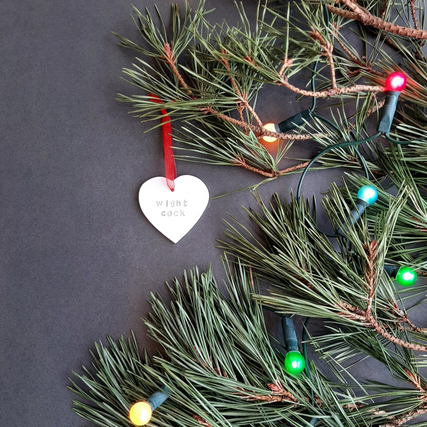 "wight cock" hanging heart decoration  shown on foliage with coloured lights